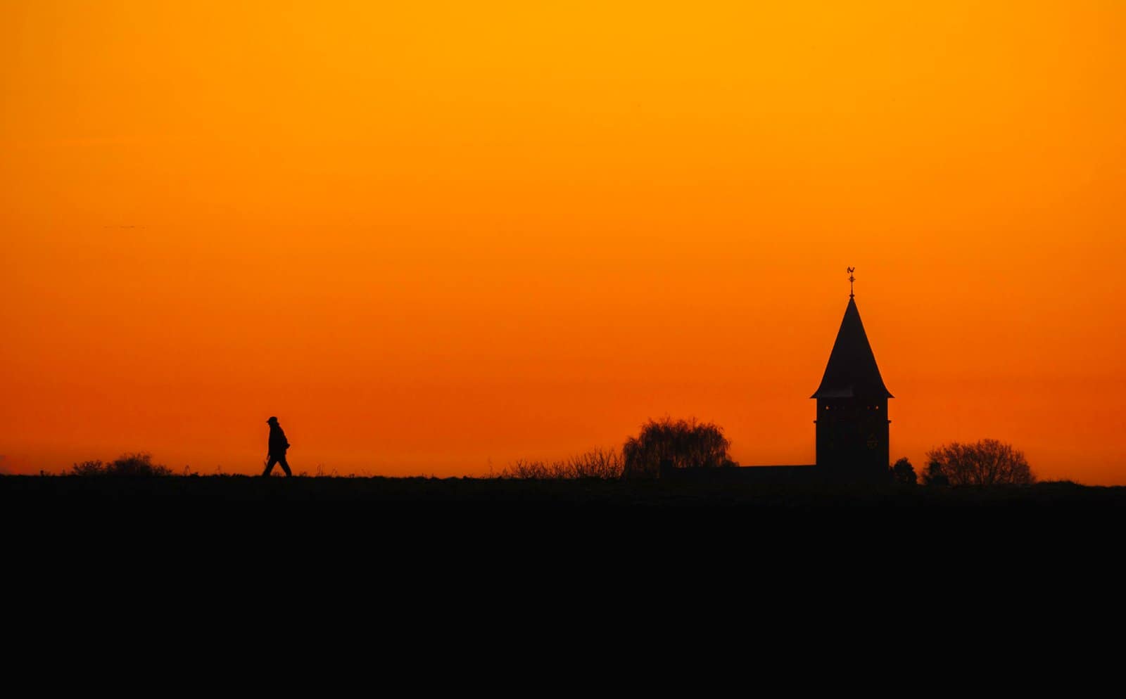 150 A silhouette of a man walking on a trail at sunrise
